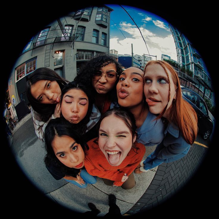 a group of women standing next to each other in front of a building with their mouths open