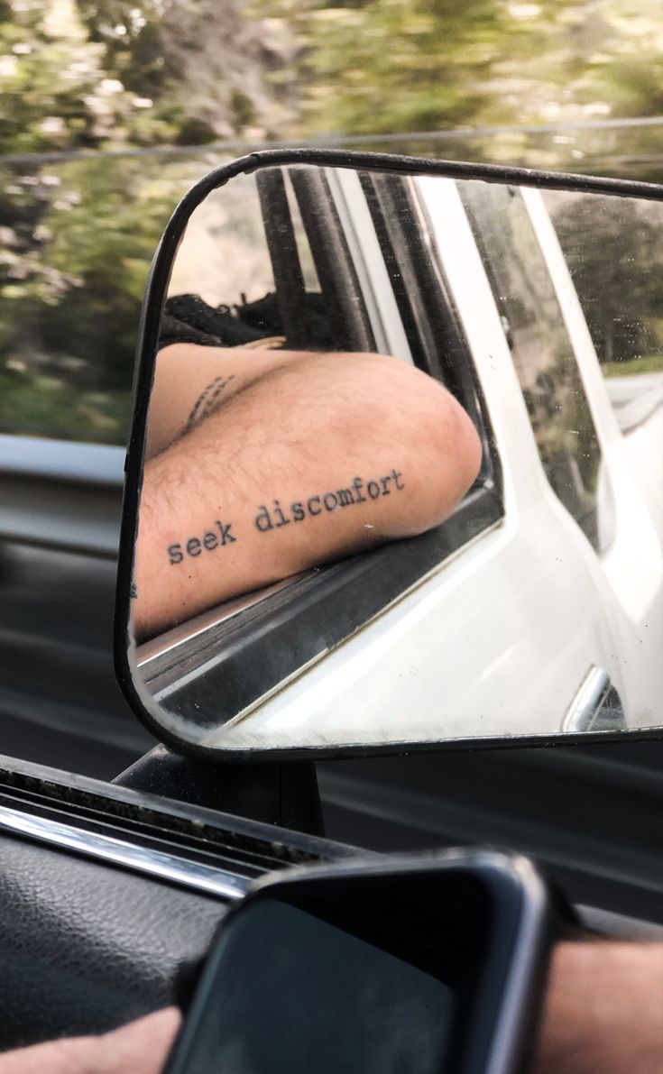 a man's arm is reflected in the side mirror of a car as he drives