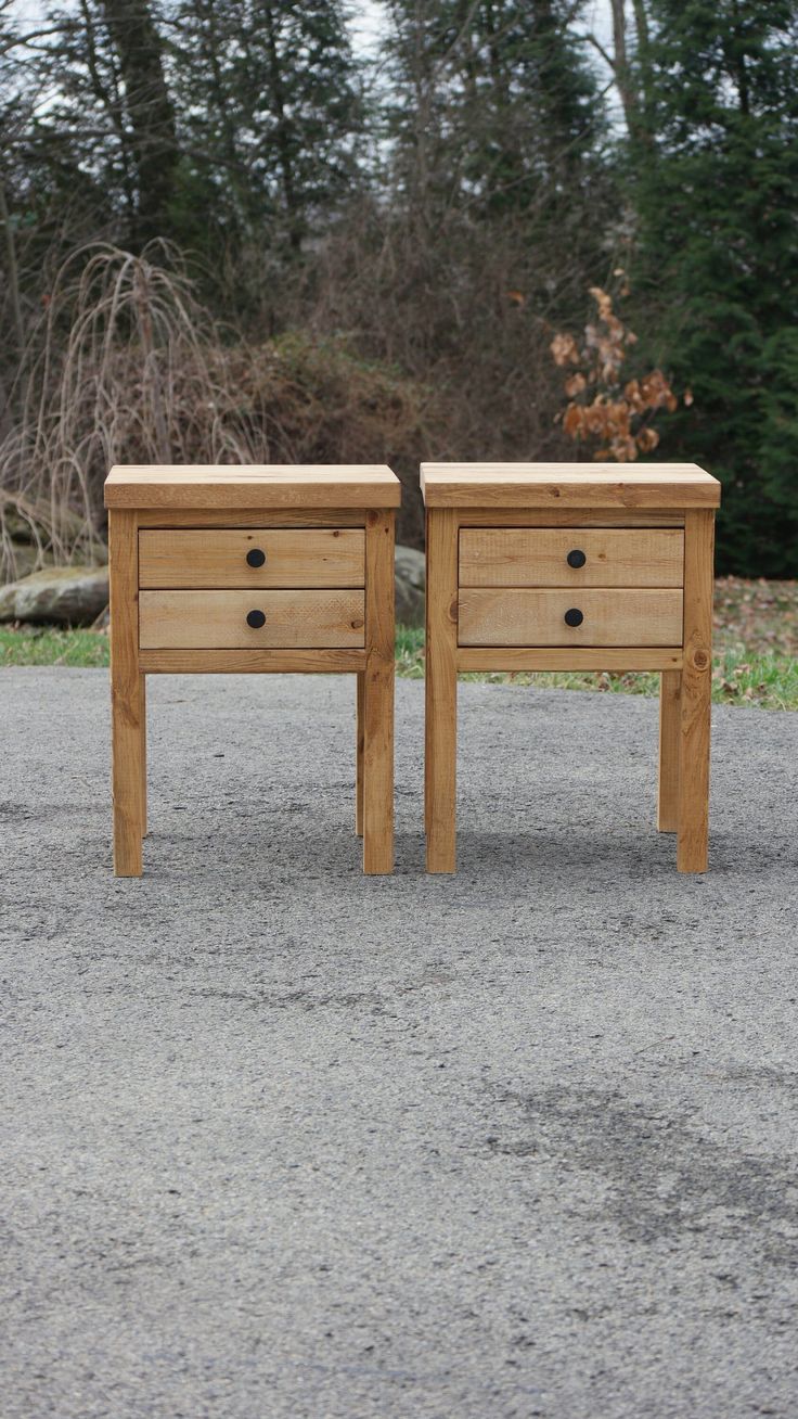 two wooden tables sitting side by side in the middle of a road with trees in the background