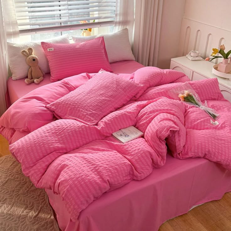 a bed covered in pink sheets and pillows