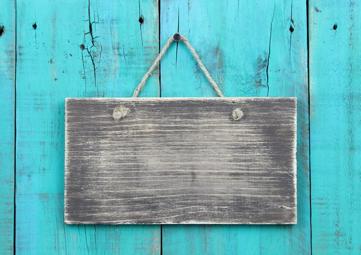 a wooden sign hanging on a rope against a turquoise wood background with copy space for your text