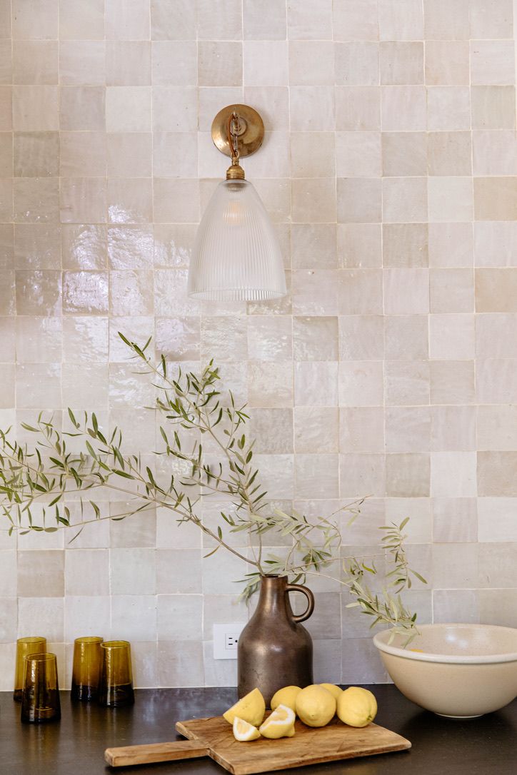 some lemons are sitting on a cutting board in front of a vase with an olive branch