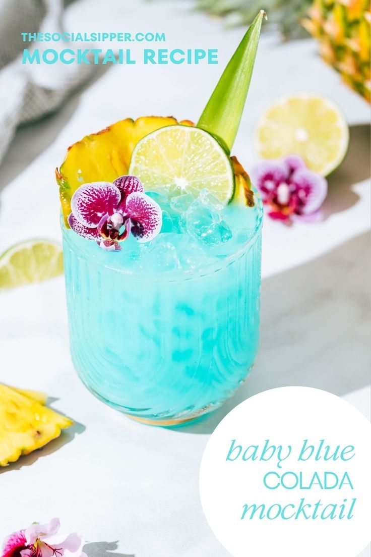 a baby blue cocktail is garnished with an orchid and lime slice for a tropical drink