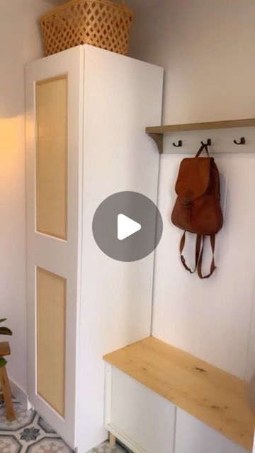 a room with a bench, coat rack and purse hanging on the wall next to it