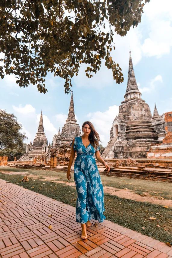 a woman in a blue dress walking down a brick walkway next to some pagodas