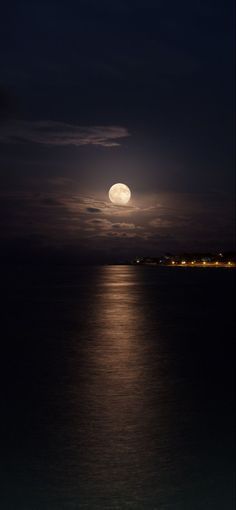 the full moon is shining over the water