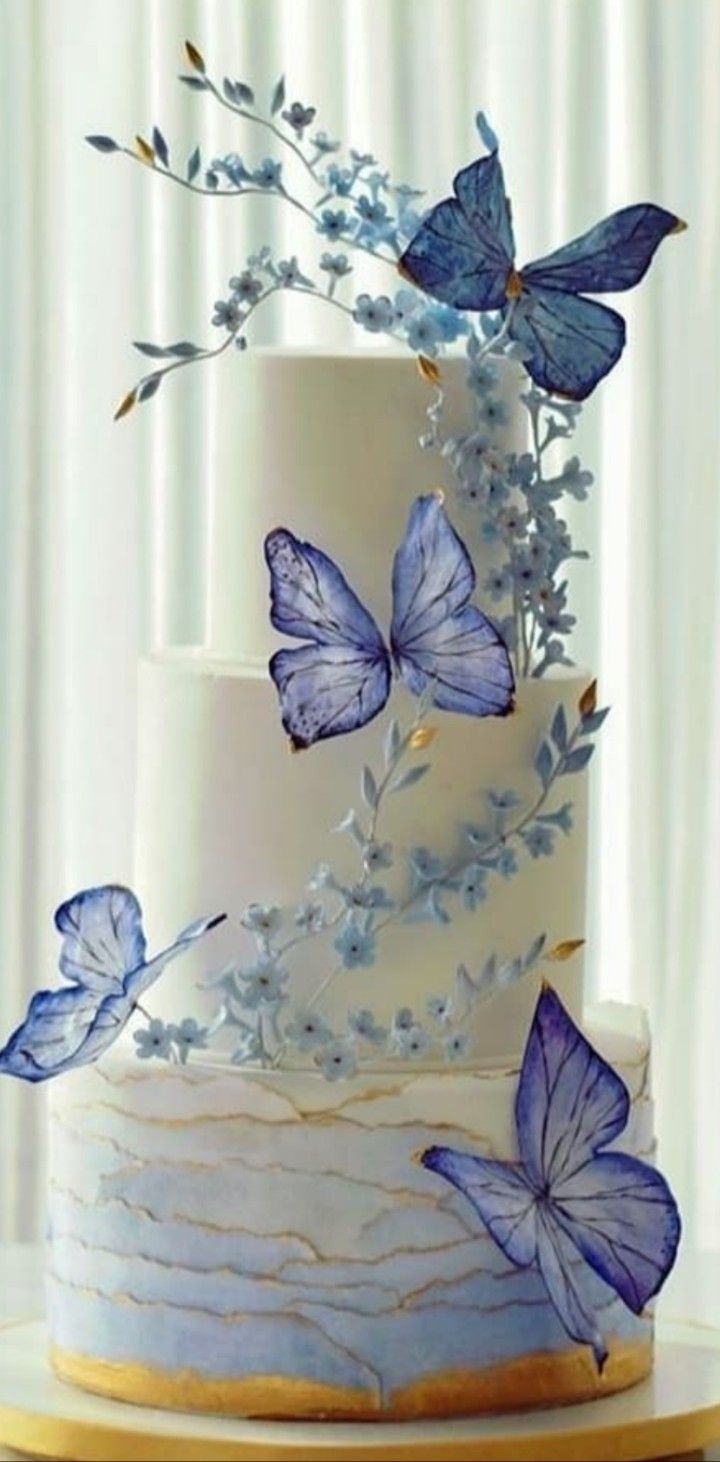 a three tiered cake with blue butterflies on it