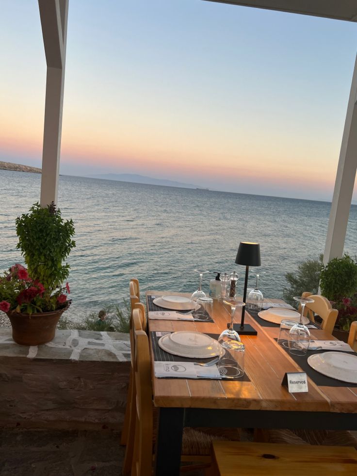 an outdoor dining area overlooking the ocean with table and chairs set up for two people