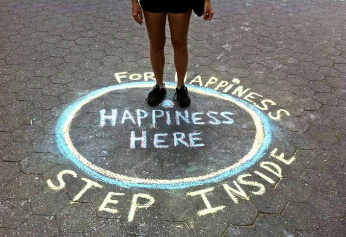 a woman standing in front of a sign that says happiness here