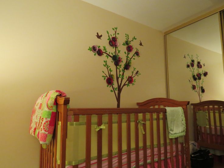 a baby crib in a room with flowers on the wall and a tree painted on the wall