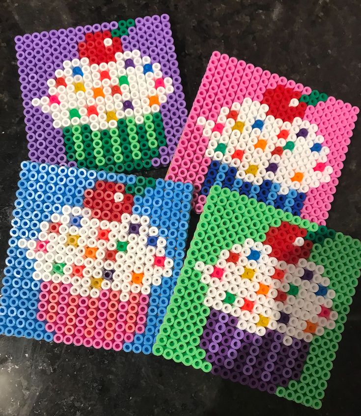 four pieces of plastic bead art sitting on top of a black table next to each other