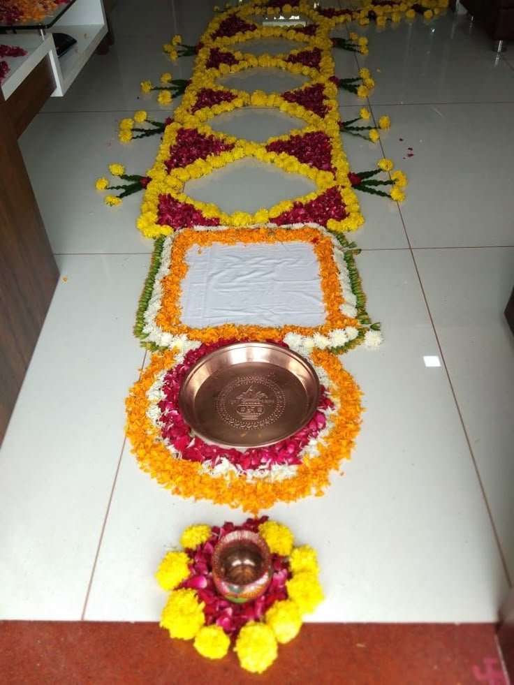 a flower arrangement on the floor next to a metal bowl