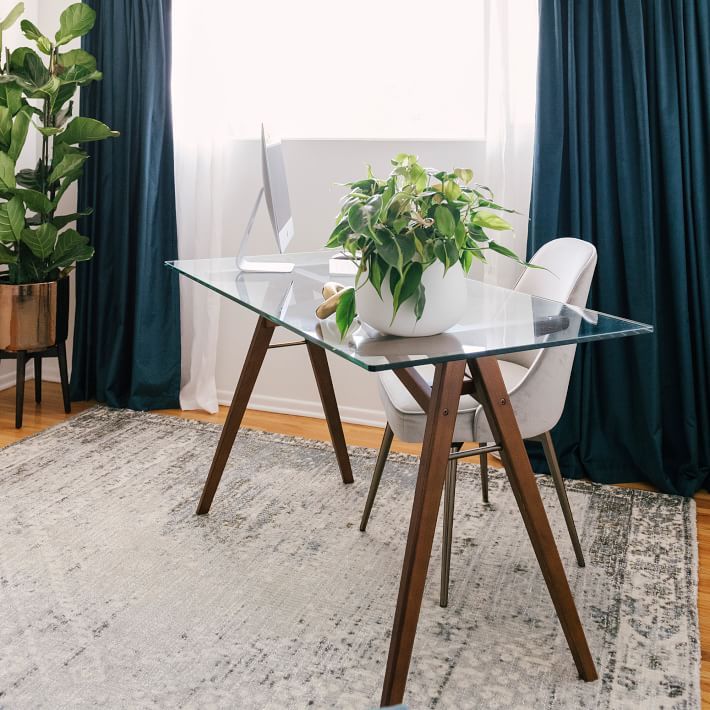 a glass table with two white chairs and a potted plant on it in front of a window