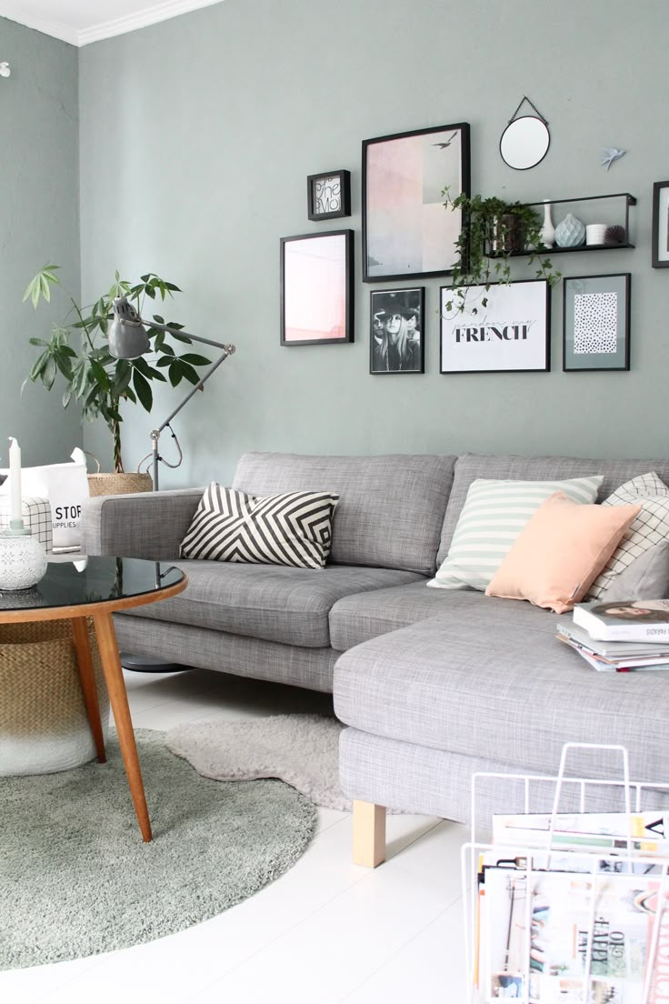 a living room with grey walls and pictures on the wall above the gray couches