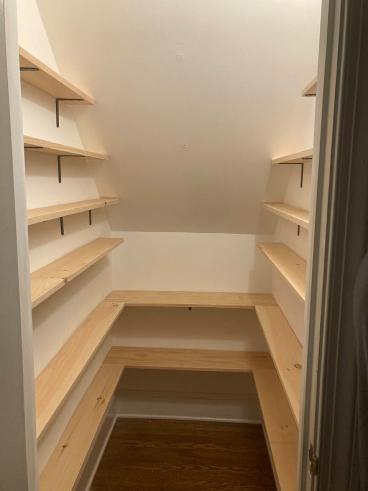 an empty walk in closet with wooden shelves