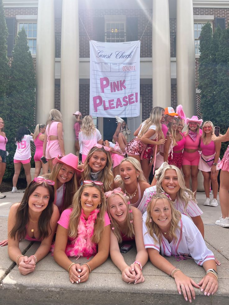 a group of young women in pink outfits posing for a photo with a sign that says pink please