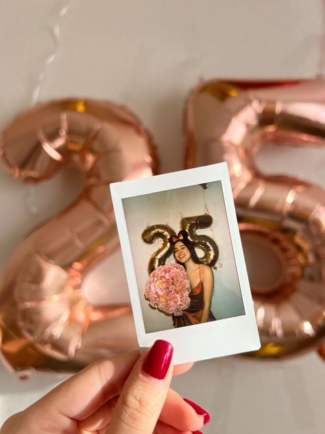 a woman holding a bouquet of flowers in front of the number twenty five balloon decorations