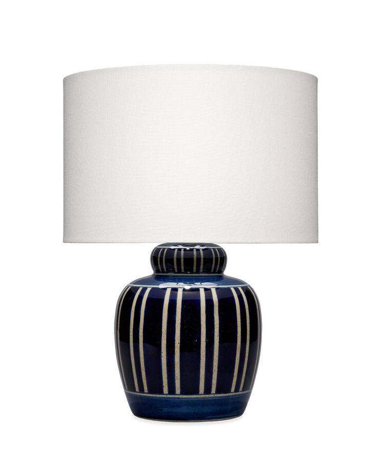 a blue and white striped vase lamp with a white shade on the top, against a white background