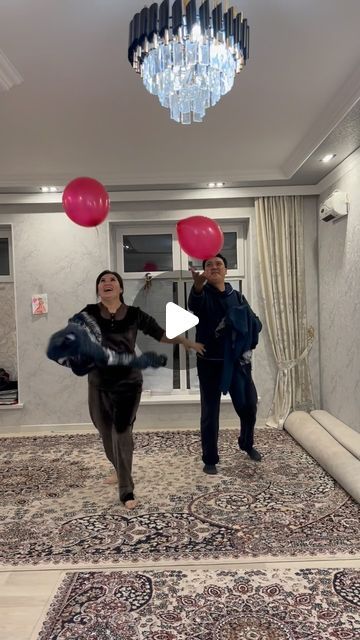 two people are playing with balloons in the middle of an area that is carpeted