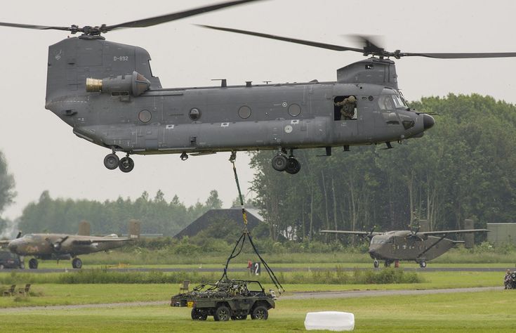 an army vehicle being lifted by a helicopter