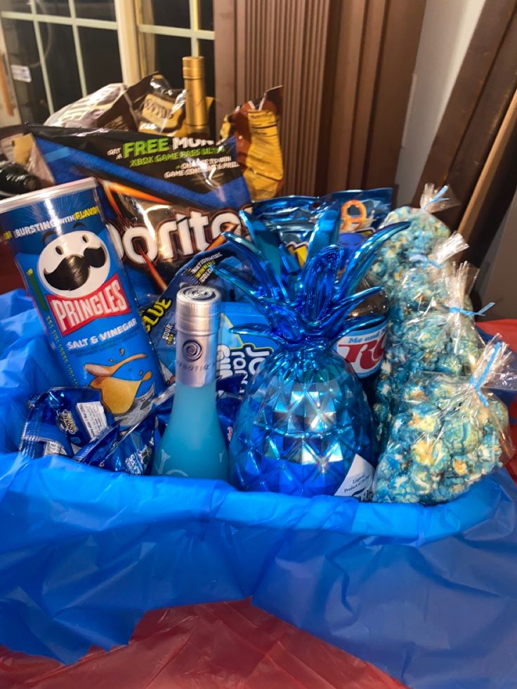 a basket filled with candy and snacks on top of a blue table cloth next to a window