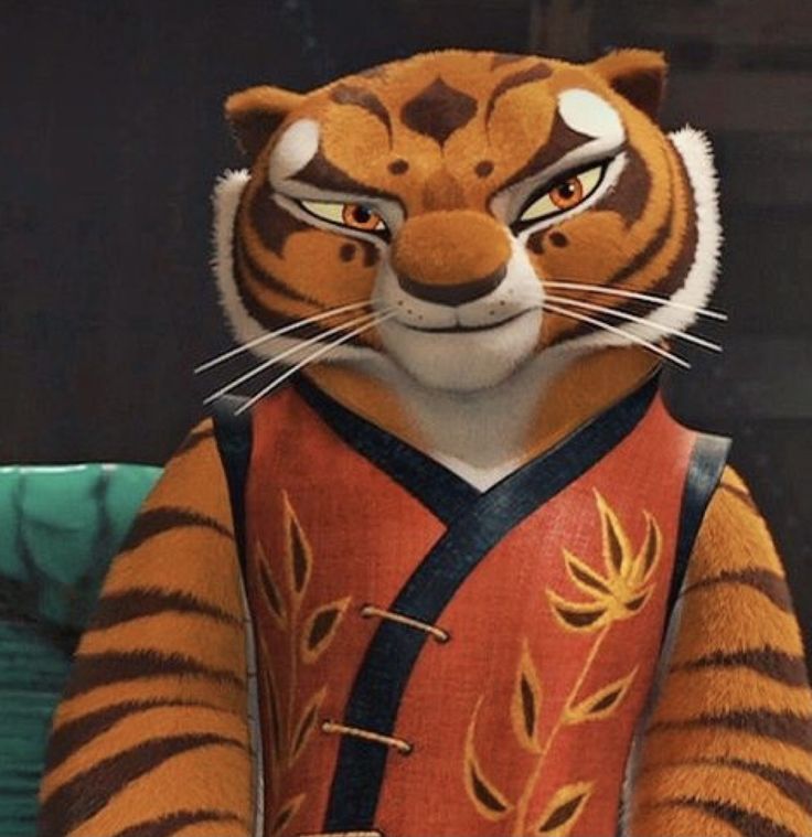 a close up of a stuffed animal wearing a red shirt and black pants with an orange tiger on it's chest