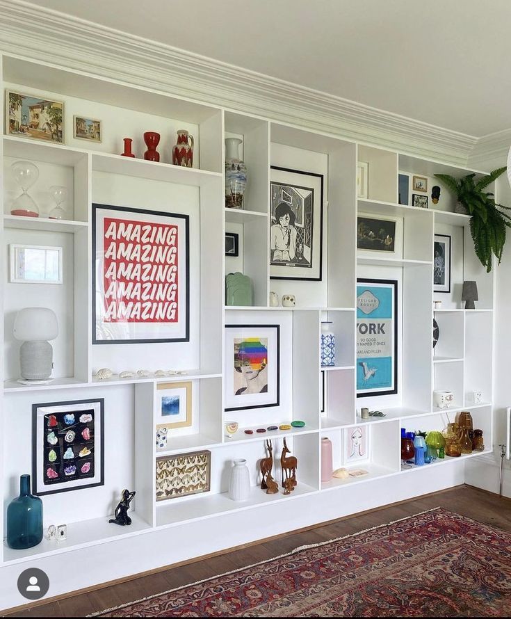 a living room filled with lots of white bookshelves and pictures on the wall