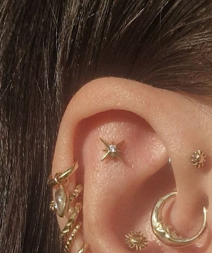 a close up of a person's ear with three different piercings on it