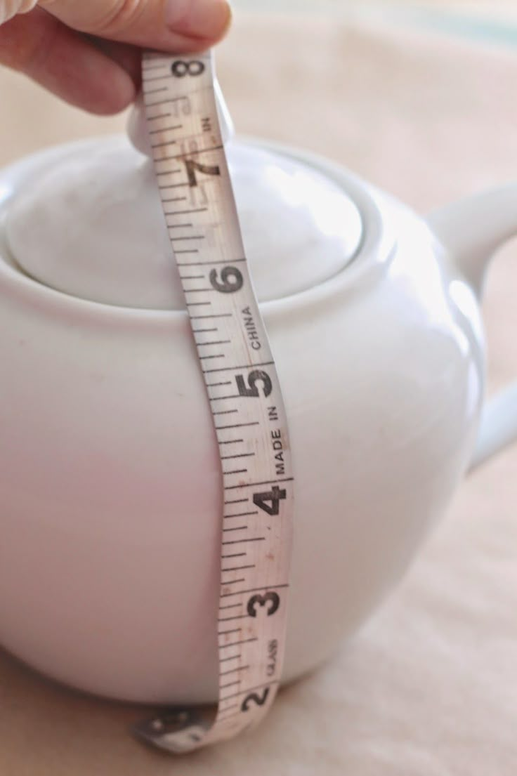 a person is measuring their teapot with a tape