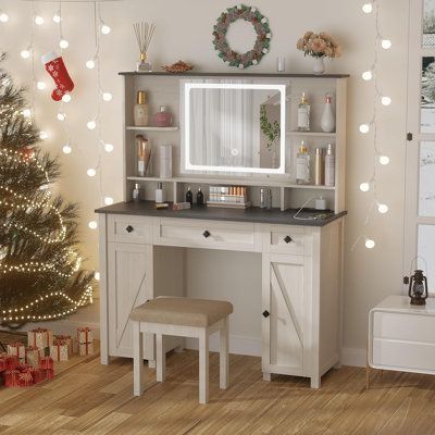 a white desk with a mirror and stool next to a christmas tree