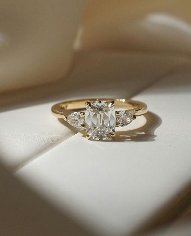 a ring with three stones on it sitting on a white cloth in the sun light