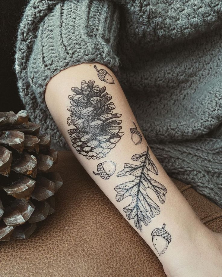 a person with a tattoo on their arm next to a pine cone and an acorn