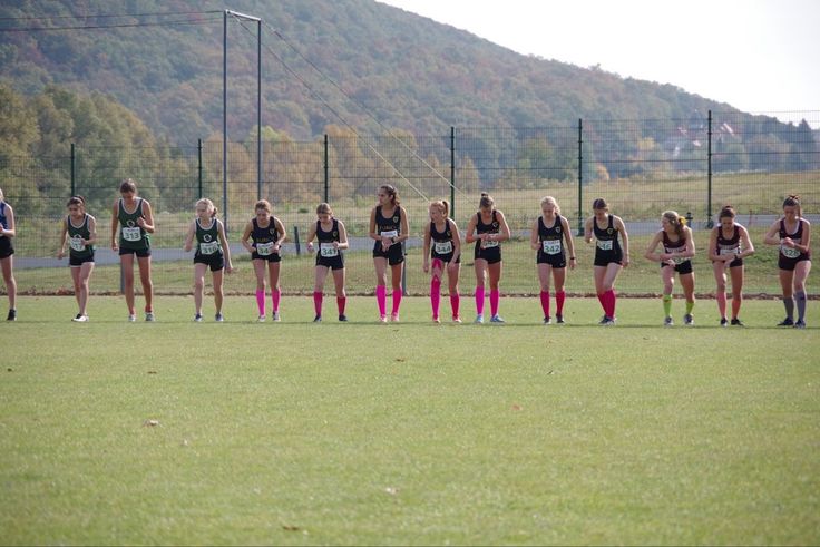 a group of women standing on top of a lush green field next to each other