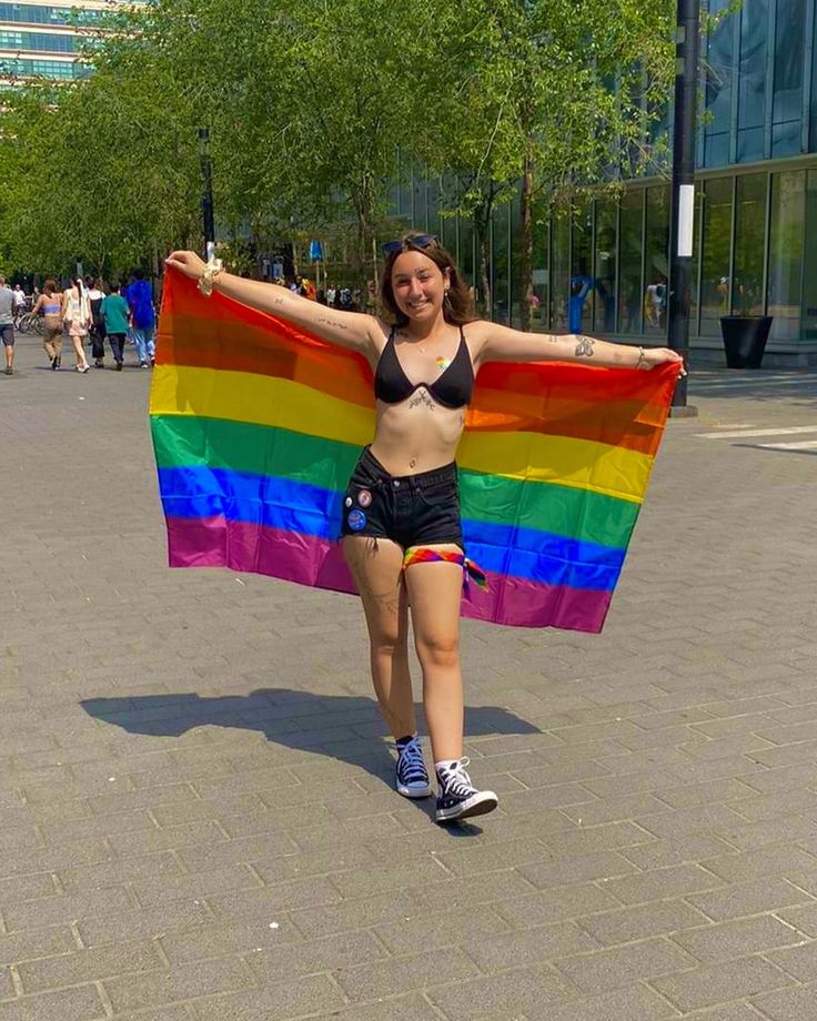 a woman is holding a rainbow flag in the street