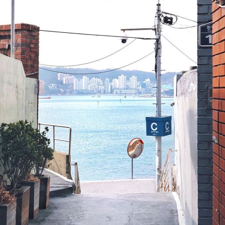 an alley way leading to the ocean with buildings in the background