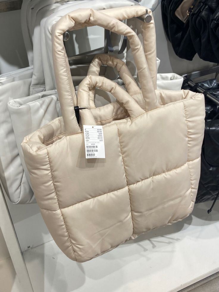 a white purse sitting on top of a counter next to other bags in a store