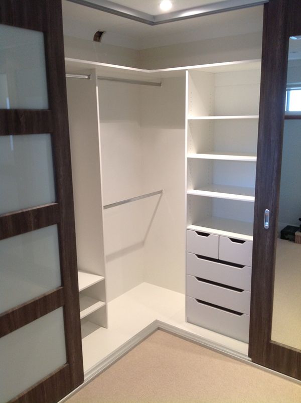 an open closet with white drawers and shelves