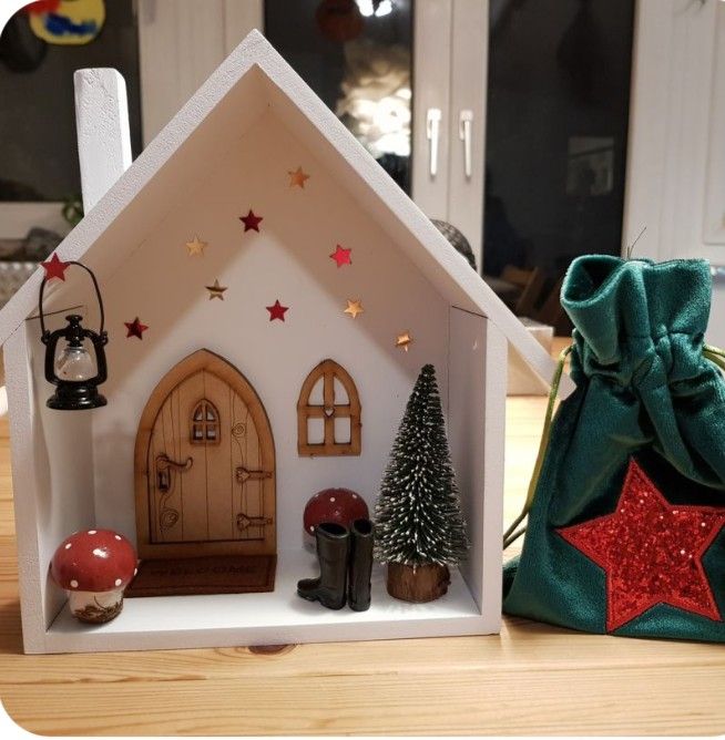 a small doll house with christmas decorations on the table