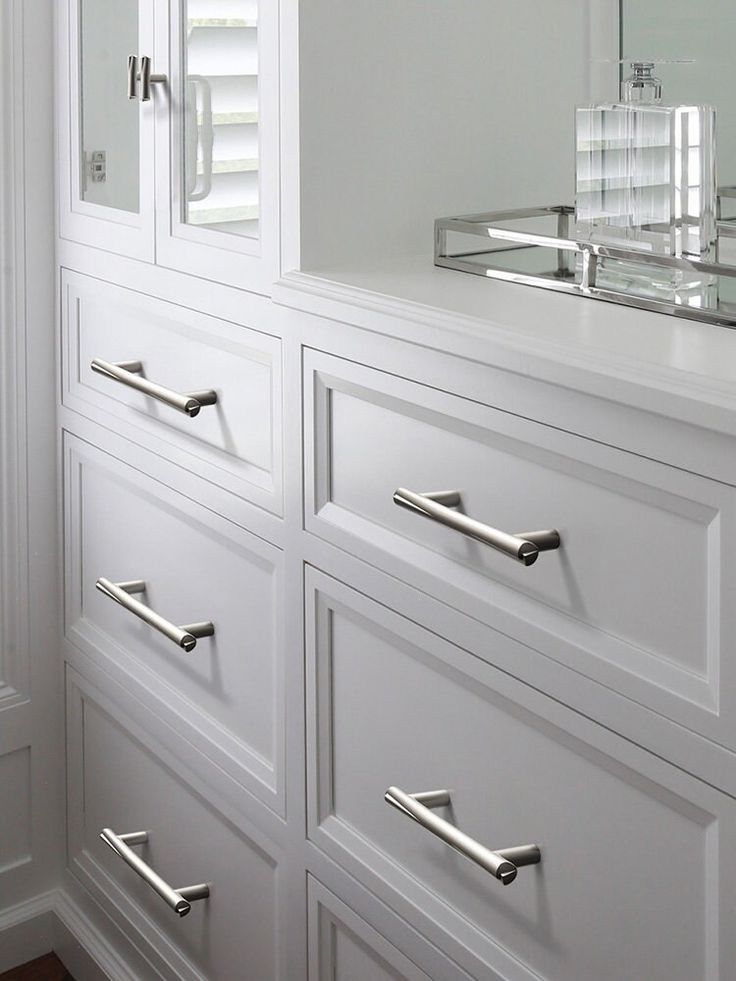 a white dresser with drawers and a mirror