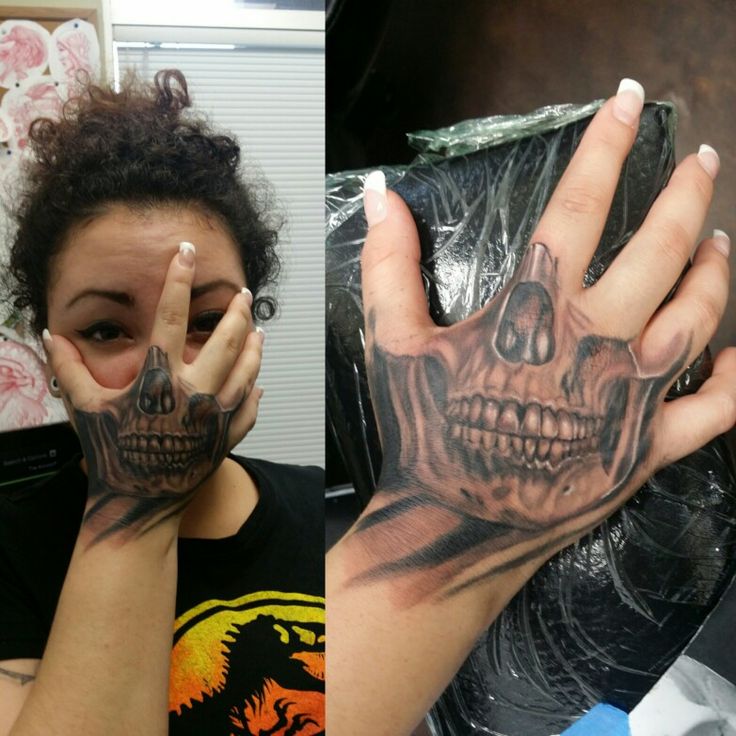 a woman holding her hands up to her face with skulls painted on it and the other hand in front of her face