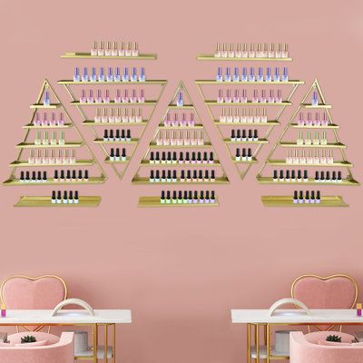 two pink chairs in front of a wall with shelves full of nail polish bottles on it