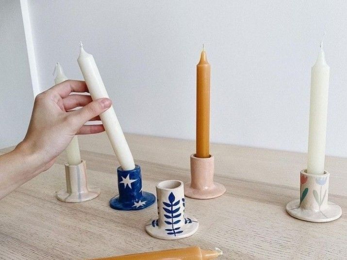 a person holding a candle in front of some candles on a table with other items