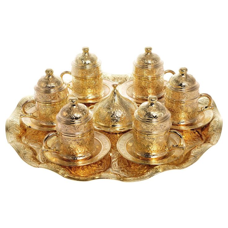 a tray that has some gold tea set on top of it with cups and saucers