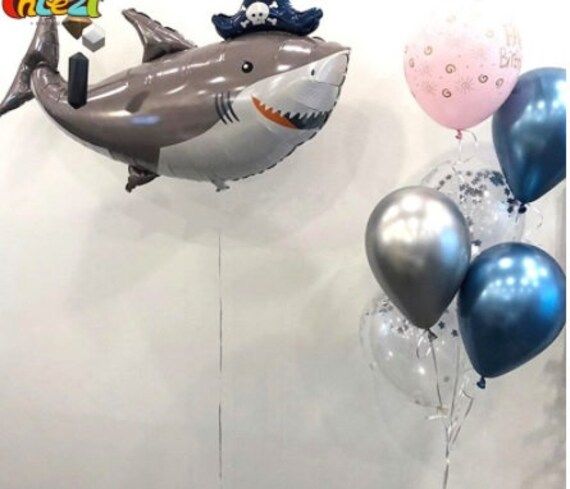 some balloons are floating in the air near a shark