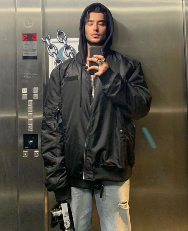 a man standing in front of an elevator holding his hand up to his face and looking at the camera