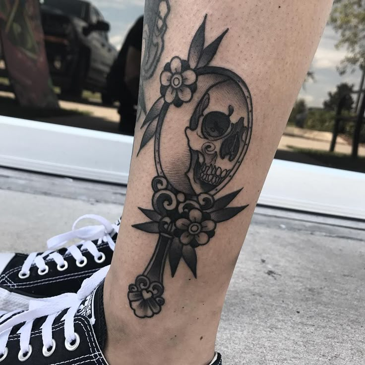 a person with a skull and flower tattoo on their leg