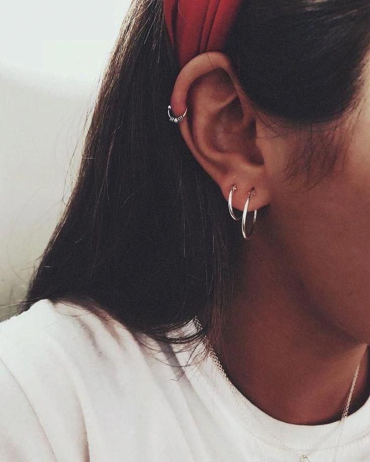 a close up of a person wearing ear rings and a white shirt with a red headband