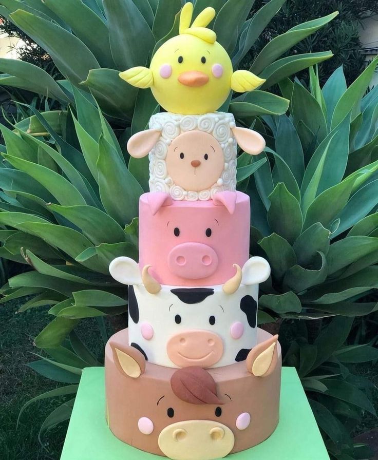 three tiered cake decorated with farm animals on top of each other and plants in the background