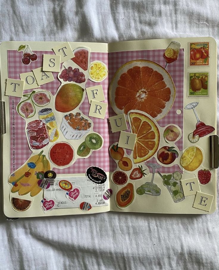 an open book with stickers on the pages and fruit cutouts attached to it