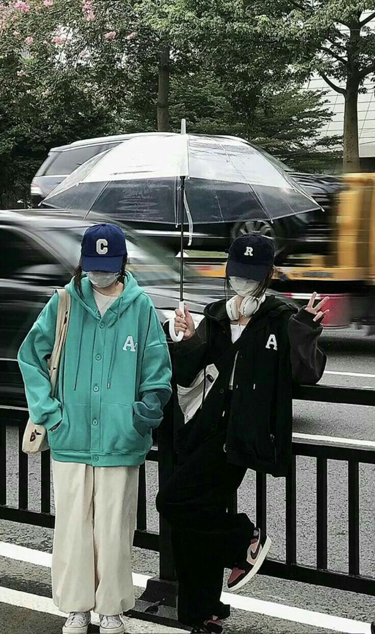 two people standing next to each other holding an umbrella